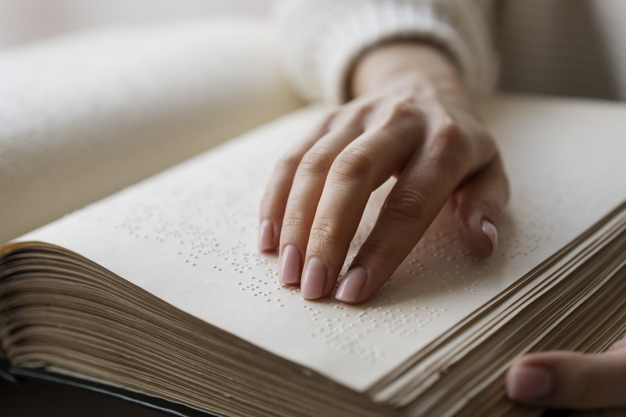 In foto: una mano scorre un libro in braille