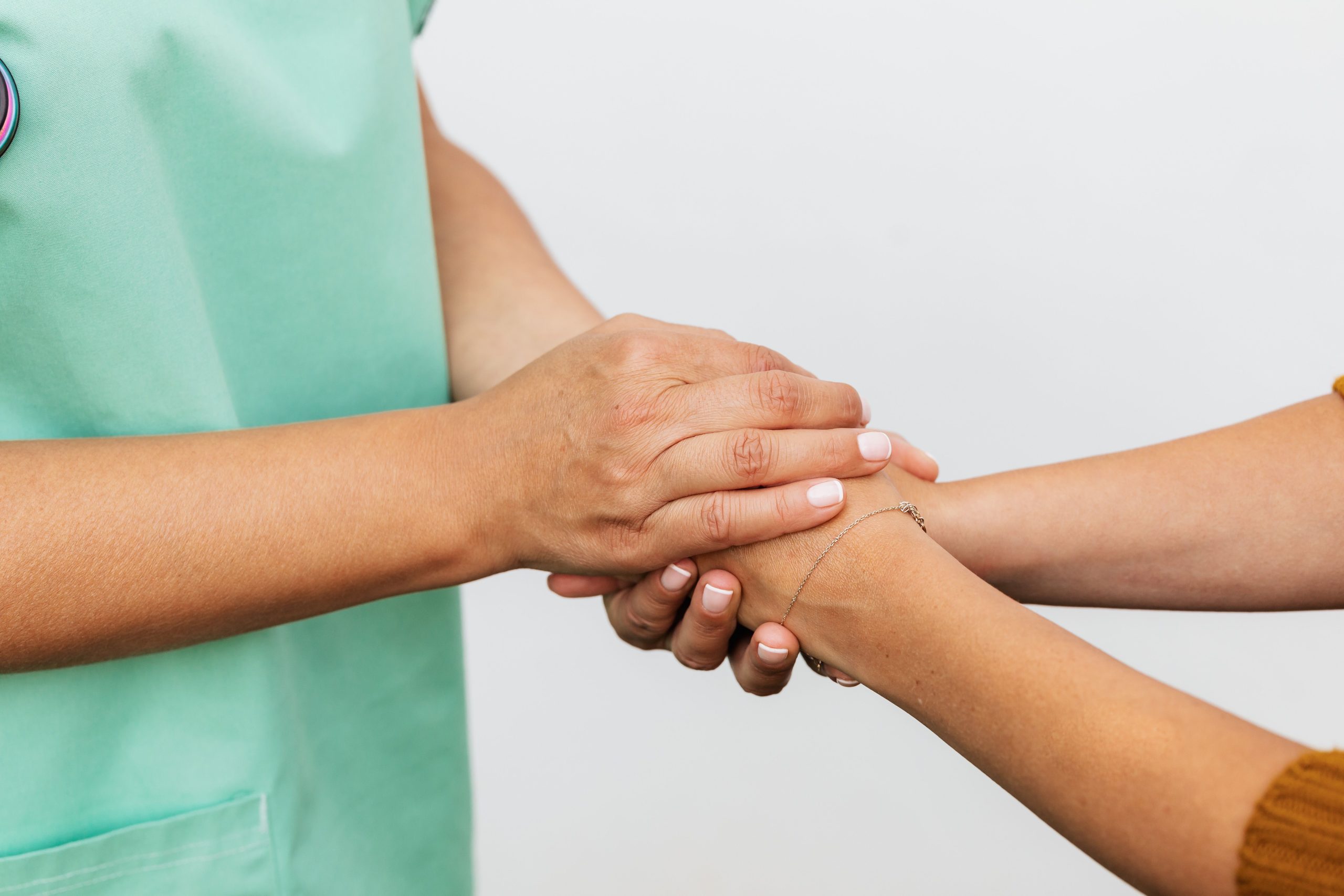 In foto le mani di un medico tengono strette le mani di un paziente