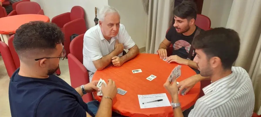 Nella foto 4 persone si sfidano a scopone scientifico