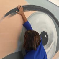In foto una persona non vedente esplora il murales di Testaccio