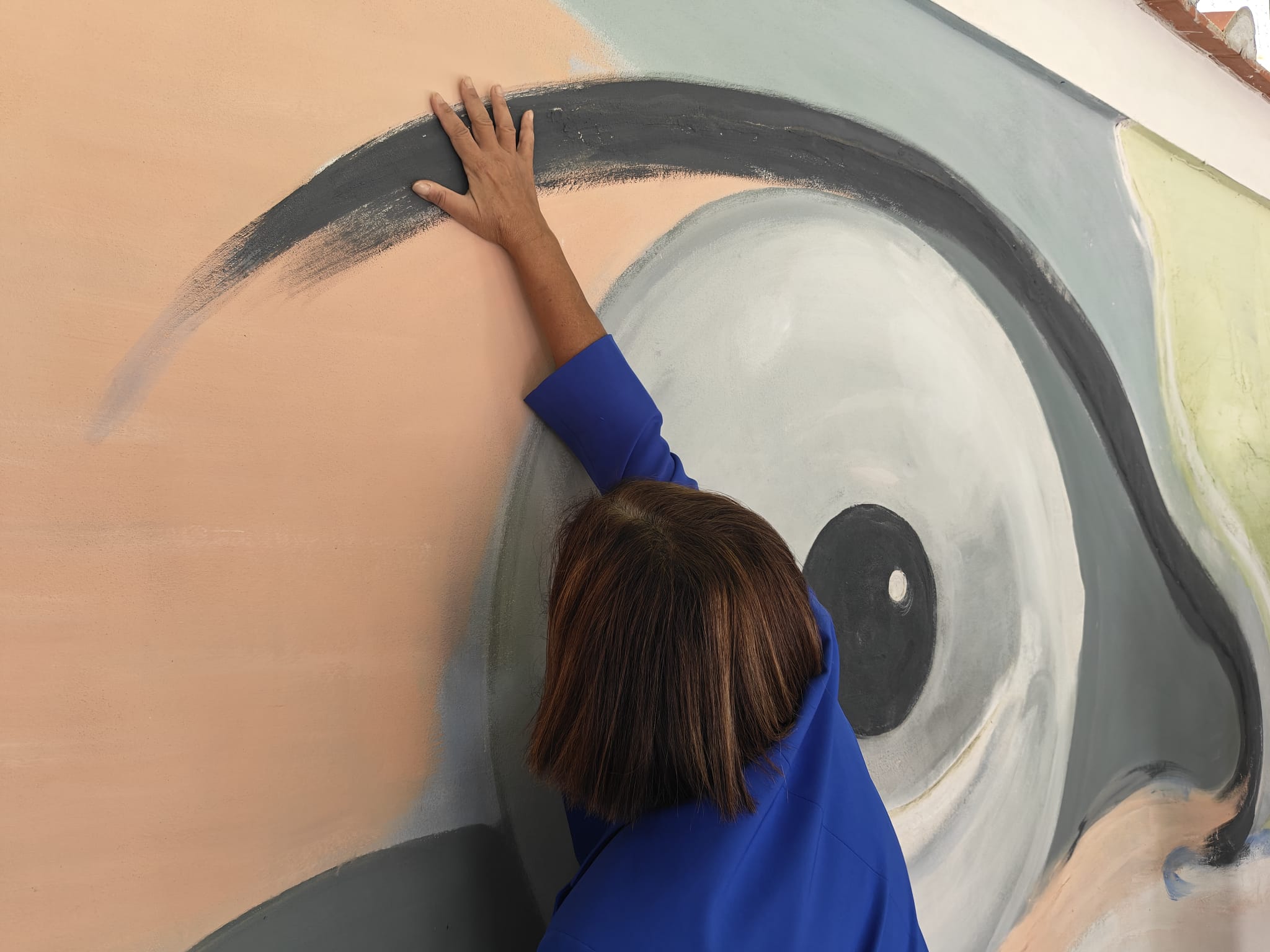In foto il murales e una persona che lo esplora con le mani